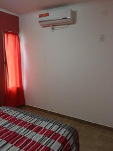 a bedroom with a bed with a red curtain and a heater at Bungalows Don Heraldo in San José