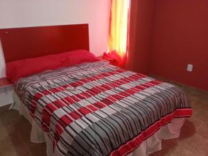a bedroom with a bed with a red headboard and a window at Bungalows Don Heraldo in San José