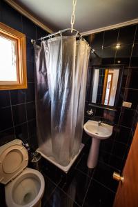 a bathroom with a toilet and a sink and a shower curtain at Hostel Chaman in Osorno