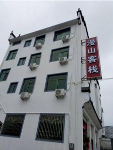 un bâtiment blanc avec un panneau sur son côté dans l'établissement Wuyuan Man Shan Inn, à Wuyuan