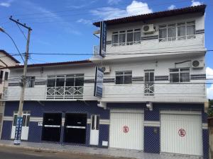 a white and blue building with two garages at Pousada Azevedo in Livramento de Nossa Senhora