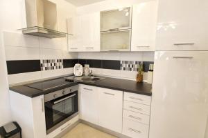 uma cozinha branca com armários brancos e bancadas pretas em Apartment Borka em Medulin