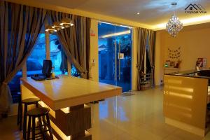 une cuisine avec un comptoir et un bar avec des tabourets dans l'établissement Tropical Villa Kuantan, à Kuantan