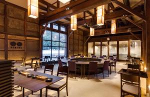 un comedor con mesas y sillas y una gran ventana en EN Takeda Castle Town Hotel, en Asago