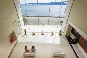 two girls sitting on the floor of a building looking out at the water at Hotel Setre Kobe Maiko in Kobe