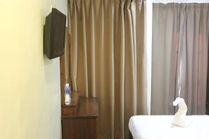 Una habitación con TV y una cama con un cisne. en Alonto Hotel, en Sandakan