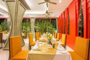 a dining room with tables and chairs and orange walls at Golden Temple Villa in Siem Reap