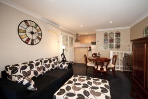 a living room with a couch and a clock on the wall at Mountain Whispers The Gatsby in Katoomba