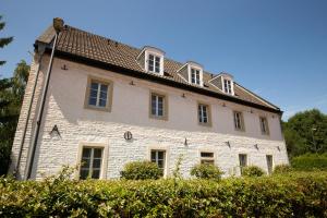 a large white brick building with a roof at Hotel Gut Grossrotter Hof (ehem. Hotel Schmitte) in Cologne