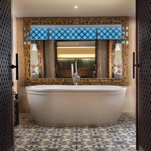 a bathroom with a tub and a large mirror at Anantara Uluwatu Bali Resort in Uluwatu
