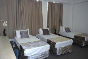 una habitación de hotel con 3 camas y cortinas en Hamilton City Inn en Hamilton