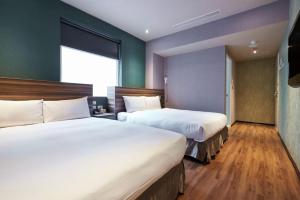 a hotel room with two beds and a window at Tomorrow Hotel in Taipei