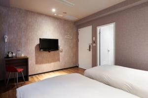a bedroom with a bed and a tv on the wall at Tomorrow Hotel in Taipei