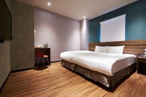 a bedroom with a large bed and a red chair at Tomorrow Hotel in Taipei