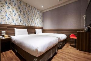 a hotel room with a large bed and a red chair at Tomorrow Hotel in Taipei