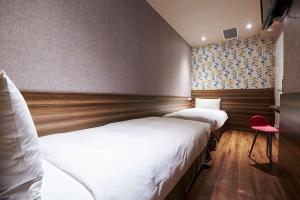 two beds in a hotel room with a red chair at Tomorrow Hotel in Taipei