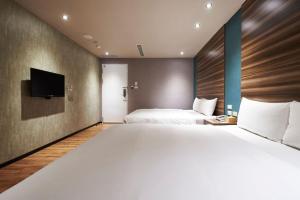 a hotel room with a large bed and a tv at Tomorrow Hotel in Taipei