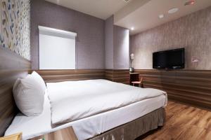 a bedroom with a bed and a flat screen tv at Tomorrow Hotel in Taipei