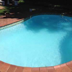 a large blue swimming pool in a yard at Rest Assured Guest House & Conference Kokstad in Kokstad