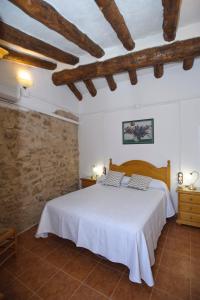 Caseta de l'Hort في Corbera: غرفة نوم بسرير ابيض وجدار حجري