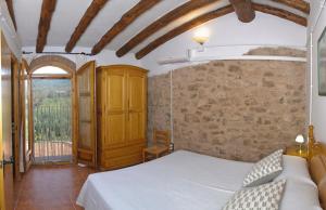 Caseta de l'Hort في Corbera: غرفة نوم بسرير وجدار حجري