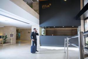 a man talking on a cell phone while holding a suitcase at Intelier Rosa in Castellón de la Plana
