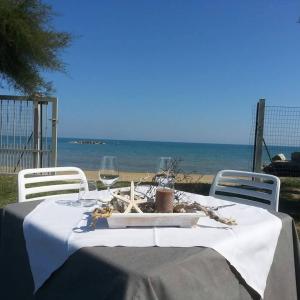 einen Tisch mit 2 Stühlen und einen Tisch mit Weingläsern in der Unterkunft Agriturismo Frontemare in Giulianova