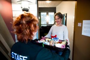 a woman holding a basket of food in a room at Holiday Linnunlahti in Joensuu