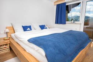 sypialnia z dużym łóżkiem z niebieskim kocem w obiekcie Apartmenthaus Lieselotte w mieście Ramsau am Dachstein