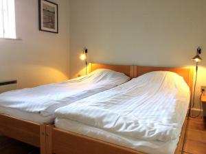 a bedroom with a bed with white sheets and two lights at Ferielejlighed på Rødkærgård in Kerteminde