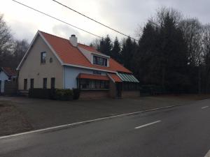 a white house with an orange roof on a street at de bron in Beringen