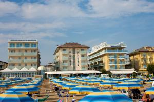 un montón de sombrillas azules y amarillas en una playa en Hotels Vidi Miramare & Delfino en Lido di Jesolo