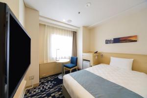 a hotel room with a bed and a flat screen tv at Kobe Sannomiya Tokyu REI Hotel in Kobe