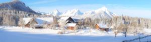 ein Haus im Schnee mit Bergen im Hintergrund in der Unterkunft Ferienhof Grossgrub in Vorderstoder