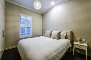 1 dormitorio con 1 cama blanca grande y ventana en Aloha Central Luxury Apartments, en Mount Gambier