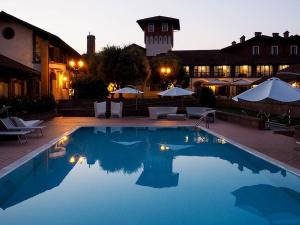 - une piscine avec des chaises et des parasols à côté d'un bâtiment dans l'établissement Relais Santo Stefano, à Sandigliano