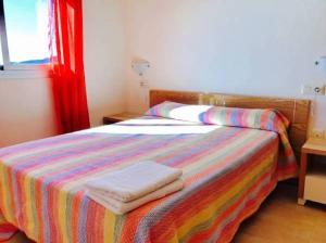 1 dormitorio con 1 cama colorida y 2 toallas en Apartamentos Deluxe Pompeya 5, en Peñíscola