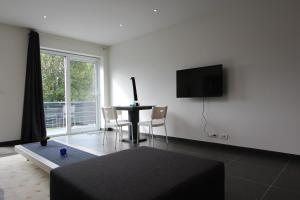 sala de estar con mesa y TV en la pared en Nuvola East en Zottegem