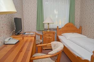 a bedroom with a bed and a desk with a television at Motel Hamburg in Hamburg