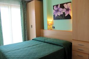 1 dormitorio con 1 cama con edredón verde y ventana en Appartamenti Grado en Grado