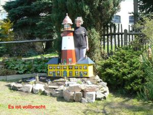 una estatua de un hombre de pie junto a un faro en Zimmervermietung-Heide-Fiege en Hartmannsdorf