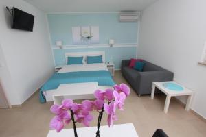 een kamer met een bed, een bank en paarse bloemen bij Studio Emanuel in Rovinj