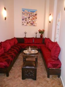 a living room with a red couch and a table at La Fontaine Bleue in Essaouira