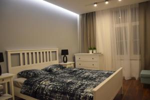 a white bedroom with a bed and a dresser at Apartament Marii Ludwiki in Koszalin