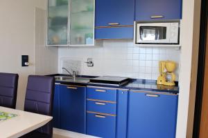 a kitchen with blue cabinets and a microwave at Appartamenti Grado in Grado