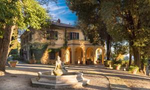 a fountain in front of a house with trees at Tenuta La Bandita in Sassetta