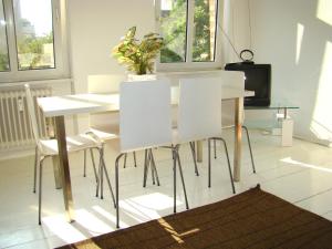 tavolo da pranzo bianco con sedie bianche e una pianta di Apartments near Kurfürstendamm a Berlino