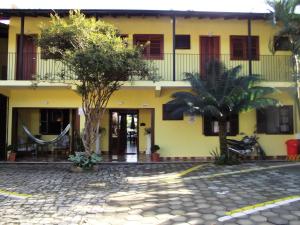ein gelbes Gebäude mit Bäumen davor in der Unterkunft Pousada Miracolo in Paraty