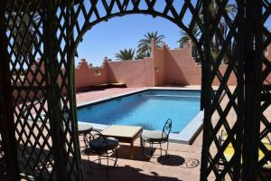 vista sulla piscina con tavolo e sedie di Hotel Carrefour des Nomades a M'Hamid