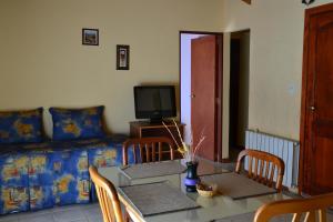 a living room with a table and a couch and a television at Alto Verde Hostería in El Calafate